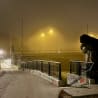 A statue is sitting on a bridge with the lights on and the fog rolling in.