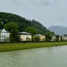 A river runs through a town with green grass on the banks and yellow buildings.