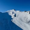 a very large snow covered mountain with a small hut at the top.