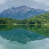 A lake is shown with a reflection of a mountain in it.