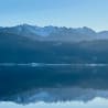 A mountain with a lake in front and a blue sky in the background.