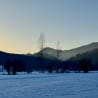 A field covered in snow with trees and a mountain in the background.