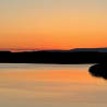The sun is setting over a large body of water, creating a beautiful reflection on its surface.