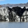 Large block of ice is seen in front of a mountain range.