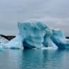 A large block of ice is resting in the ocean surrounded by water.