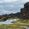 A river runs through a rocky landscape with huge cliffs on either side.