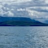 The ocean meets the clouds and the land rises up from the water.