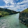 A river flows through a rocky canyon with a grassy bank on either side.