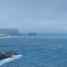 A large body of water with three rock outcroppings in the distance.