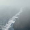 An aerial view of a wetland with waves crashing against the shore.