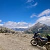 A motorcycle with a helmet on it parked on a mountain side.