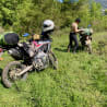 A man is sitting on a motorcycle in the grass with a white helmet on his head.