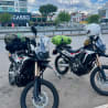 Two motorcycles with helmets on them parked next to a building.