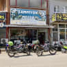 Several motorcycles are parked in front of a small store.