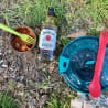 A bottle of Jim Beam is on a rocky area with a fork and spoon on the ground next to it.