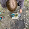 A person is making coffee over a campfire using a camping pot.