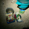 A small amount of food is sitting on a rocky ground next to a knife and a can of beans.