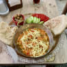 A metal serving platter is filled with food including pieces of bread and tomatoes, and also has cheese on it.