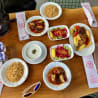 A table with many different foods on it and a couple of forks and knives on the side.