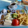 A breakfast plate with eggs, tomatoes, and cheese along with a side of fries and a drink.
