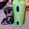 A pair of brown boots sits next to a green bag.