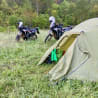 Two motorcycles are parked next to a tent on a grassy area.
