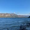 A lake with mountains in the background is calm and still.