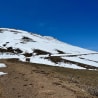 A large body of snow covered ground with a lone hiker in the distance.