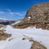 A road covered in snow is shown with mountains in the background.