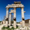 Four large columns with stone tops that are weathered and missing pieces of stone.