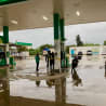 People are getting gas at a station on a rainy day.