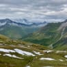 A view of mountains and a valley with snow on the mountains and a stream in the valley.