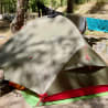 A tent is set up on a grassy area with trees in the background.