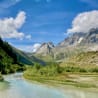 A mountain stream with trees and a blue sky in the background.
