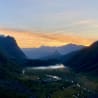 A valley with a sunset behind it and mountains in the background.
