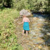 A woman in a blue skirt is walking through water in a stream.