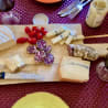 A wooden cutting board with various foods on it, including some type of meat and cheese, and a bottle of wine.