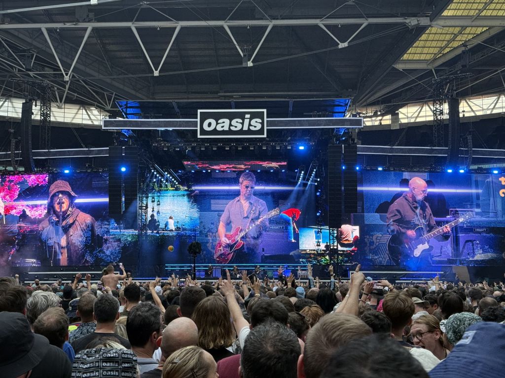 Oasis on stage at Wembley. Liam, Noel and Bonehead on the big screens.