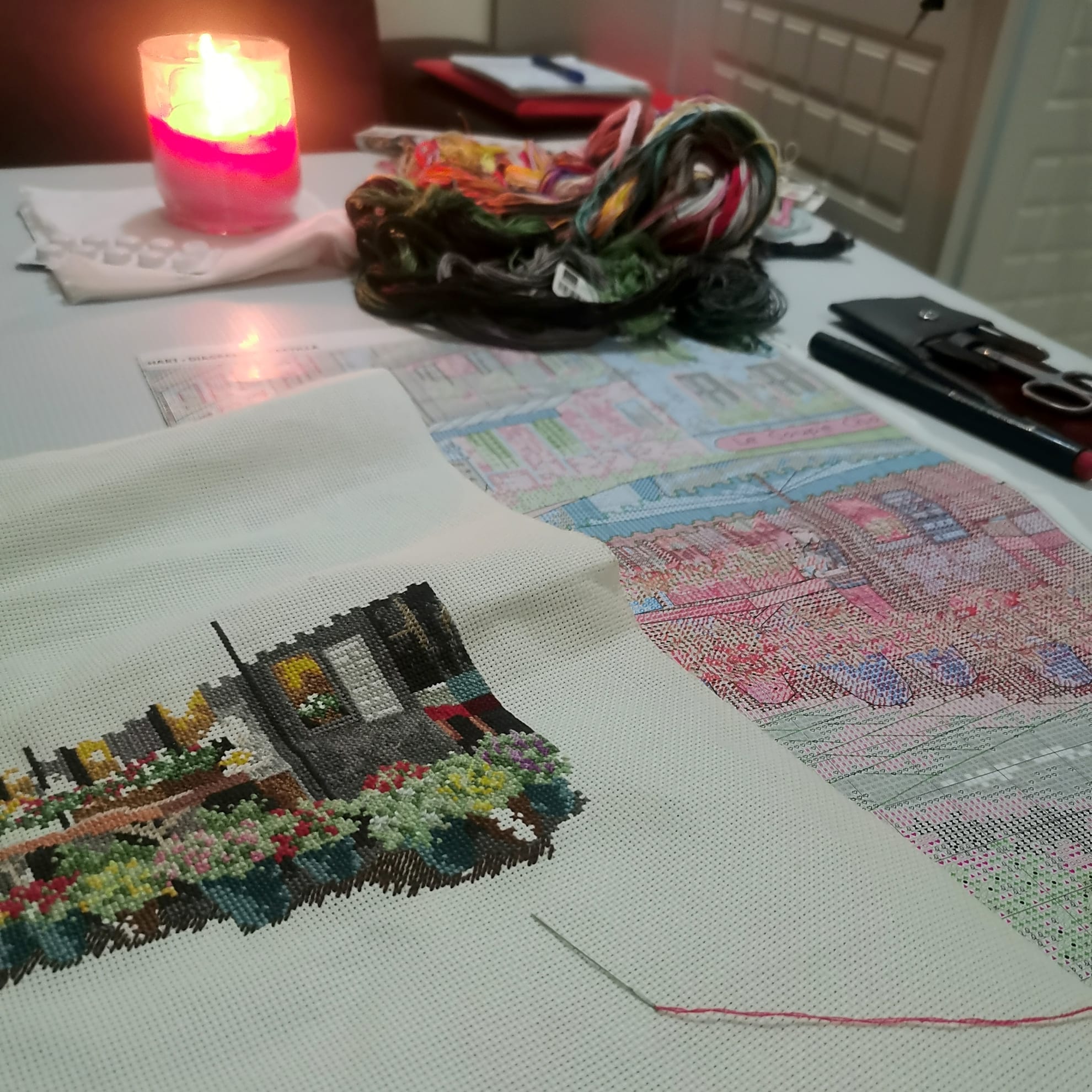 Процесс вышивки на ткани с нитками и схемой на фоне