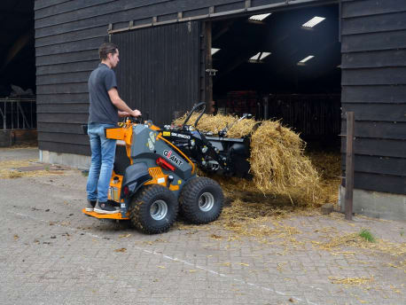 Mann schiebt Heu mit Giant Skidsteer Lader in die Scheune