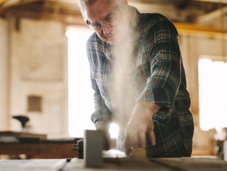 Mann sägt Holz an Werkbank