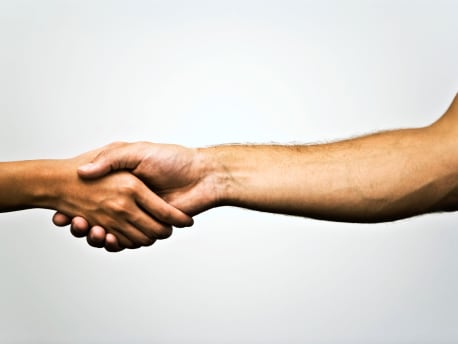 Das Bild zeigt zwei Hände, die sich die Hand geben