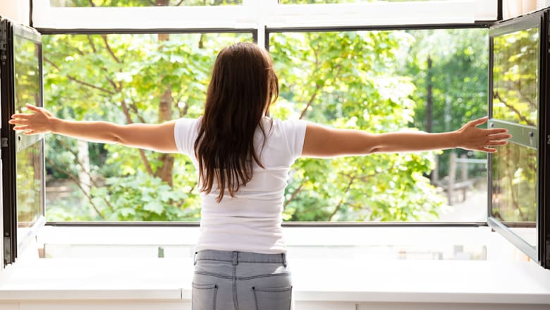 Frau vor geöffnetem Fenster