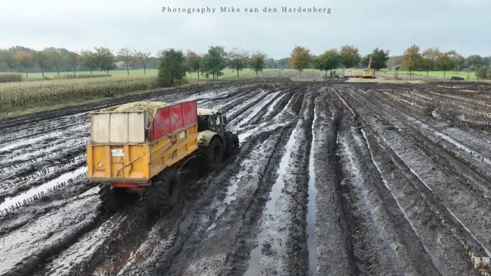 Ein Gespann aus Traktor und Kipper fahren über ein extrem schlammiges Maisfeld