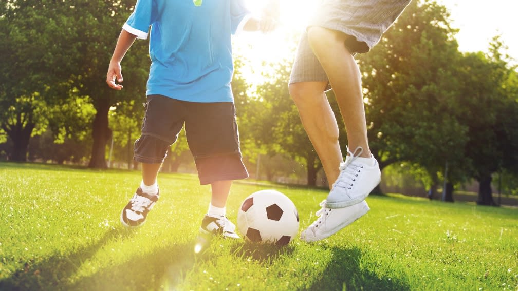 Zwei Personen spielen auf einer Rasenfläche Fußball