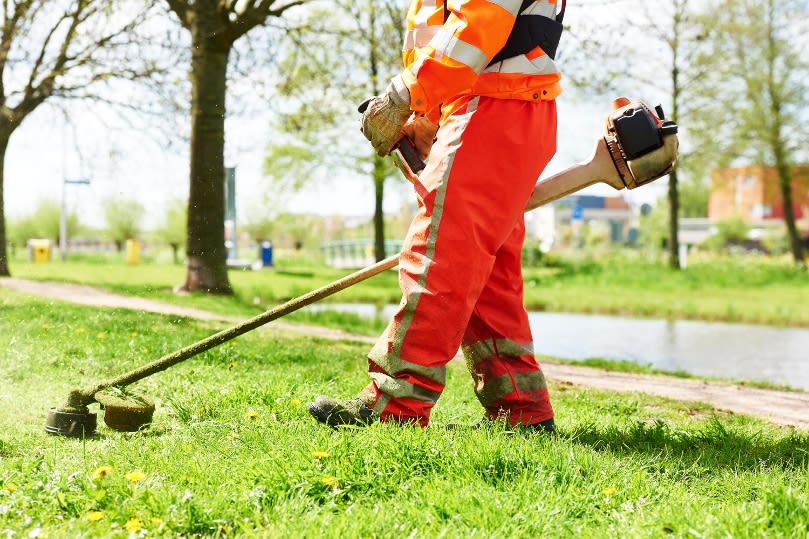 Arbeiter der Gartenarbeit macht mit einer handgeführten Maschine