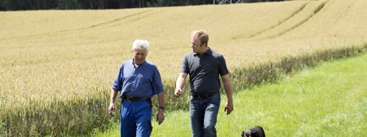 Two men with dog  walking on a field