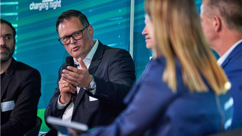 The picture shows a closer section of the panel discussion. Matthias Maedge is speaking into the microphone.