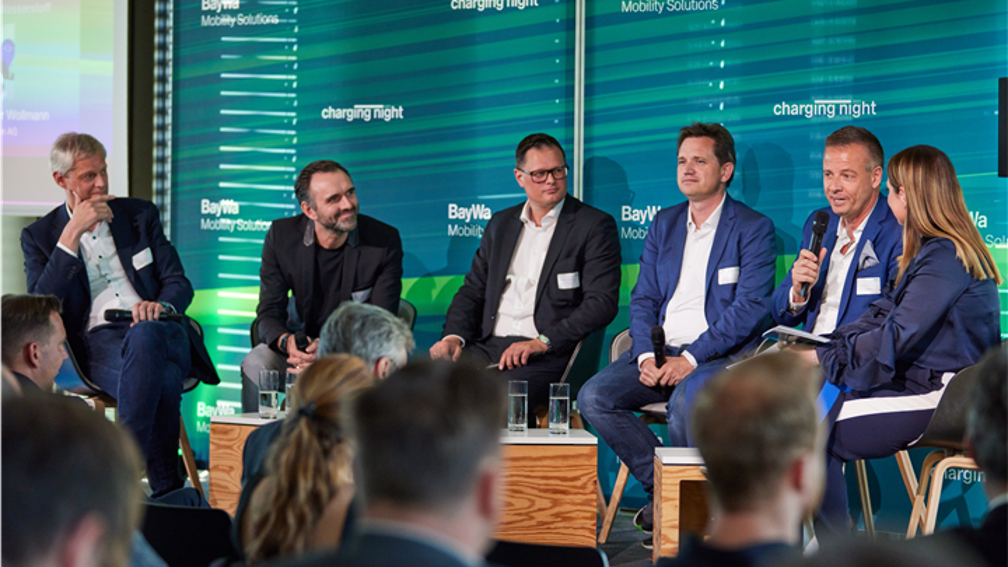 Die Teilnehmer der Podiumsdiskussion sitzen im Halbkreis auf der Bühne und sind mitten in der Diskussion.