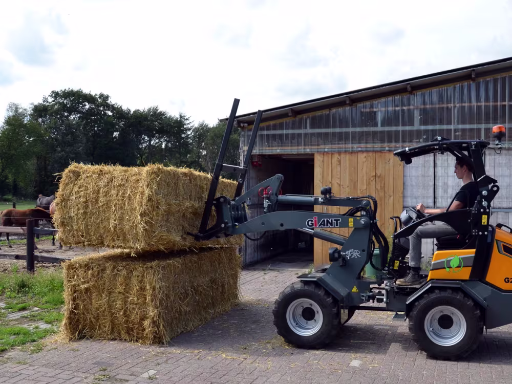 Landwirt stapelt Heuballen mit dem GIANT Elektrolader G2200E